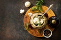 Dumplings baked in a pot with mushrooms and sour cream sauce on a stone or slate background.