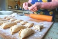 Dumplings close-up, on the background of the elderly female hands make dumplings stuffed with cottage cheese. dumplings or pies,