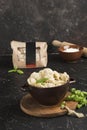 Dumplings in eco-friendly paper packaging for delivery and a bowl with dumplings, basil and sour cream on a dark background