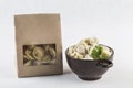 Dumplings in eco-friendly paper packaging for delivery and a bowl of dumplings on a white background, isolated