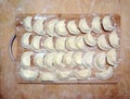 Dumplings with filling on a wooden board in flour. top view. raw frozen. traditional meal. Many dumplings on the Board in flour.