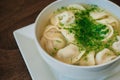 Dumplings with meat in broth with herbs in a white plate on a dark background. Russian folk cuisine. White bowl on a wooden table Royalty Free Stock Photo