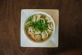 Dumplings with meat in broth with herbs in a white plate on a dark background. Russian folk cuisine. White bowl on a wooden table Royalty Free Stock Photo