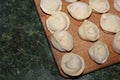 Dumplings on a wooden board on a green background. Top view on a green table with homemade food. Uncooked handmade dumplings on a