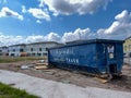 A dumpster full of trash in the yard of a new townhome that is under construction in Laureate Park Lake Nona Orlando, Florida