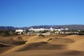 Dunes with city and mountain on horizon with blue