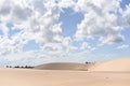 Dunes covered by scattered white clouds against a beautiful blue sky on a sunny day Royalty Free Stock Photo