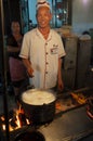 Street scene in the city of Dunhuang, with a cook preparing lamb kebab at a food stall, in China