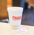 Dunkin donuts cup of hot coffee and sugar sachet on table Royalty Free Stock Photo