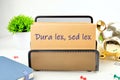 Dura Lex Sed Lex. A Latin phrase meaning The law is harsh, but it is (still) the law. on the mustard-colored card