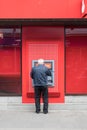 Adult man using a atm cash machine in Santander livery in the street Royalty Free Stock Photo