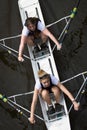 Two female rowers in race with one looking up to camera. Overhead shot