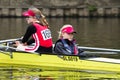 Two young female athele rowers in a yellow boat waiting for a regatta race to start looking bored and cold