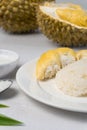 Durian sticky rice with pandan leaves, sugar and coconut milk against blurry durian fruits background. selective focus