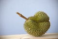 Durian on wooden table against flat color background