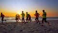 Football sport team is engaged in jogging training at sea at sunset