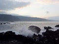 Dusk Along Rocky Shore with waves crash along rocks and clouds in the sky Royalty Free Stock Photo