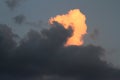 At dusk, in a cloudy sky, the last rays of the sun illuminate a cloud of vertical development Royalty Free Stock Photo