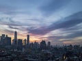 Dusk falls over the New York City skyline with the lights of the skyscrapers contrasted against the colorful evening sunset