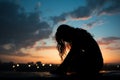 Dusk melancholy Silhouette of a woman, head bowed in sorrow