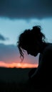 Dusk melancholy Silhouette of a woman, head bowed in sorrow