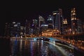 Dusk photo of illuminated Singapore commercial district waterfront reflected in the water of the Marine Bay