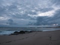 Dusk on the rocky beach with dark, gray, cloudy sky