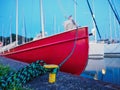 dusk view on red bow of old sailboat moored with rope to metal bollard on a coast Royalty Free Stock Photo