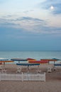 Dusky seascape with colorful beach umbrellas and white wood fence Royalty Free Stock Photo