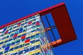 Low angle symmetrical view beyond colorful skyscraper facade with windows against dark blue clear cloudless sky