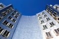 Low angle view on Gehry house with curved silver shiny futuristic metallic aluminium facade with windows against dark blue clear c