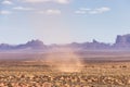 Dust Devil on a hot sunny day in a desert with red rocky mountains in background Royalty Free Stock Photo