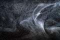 Dust particles cloud generating abstract shapes with black background and copy space for text.
