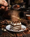 Dusting tiramisu-like cake with cocoa powder. Still life with slice of cake and coffee and cacao beans on wooden table