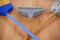 Dustpan, sweeping broom and mop on wooden floor