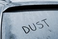 Dusty rear car windshield with word Dust written