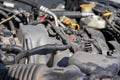 Dusty details of a flat-four boxer car engine compartment under the open hood. Alternator and intake manifold