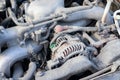 Dusty details of a flat-four boxer car engine compartment under the open hood. Alternator and intake manifold