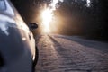 Dusty dirt road on a beautiful sunset behind the forest, in the front and background silhouettes of cars Royalty Free Stock Photo