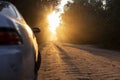 Dusty dirt road on a beautiful sunset behind the forest, in the front and background silhouettes of cars Royalty Free Stock Photo