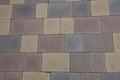 Dusty surface of pavement made of pink, yellow, brown and gray concrete blocks