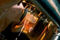 Dutch angle shot of a barman wearing a white shirt pouring craft beer into a glass