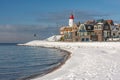 Dutch beach covered with snow and view at lighthouse Urk