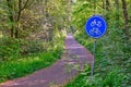 Dutch bicycle lane surrounded forest, round blue sign only bike and mopeds allowed