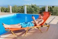 Dutch boy on sunlounger operating mobile phone at pool Royalty Free Stock Photo