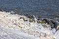 Dutch breakwater with basalt stones covered with ice in wintertime