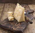 Dutch cheese with holes on a wooden old board and cheese knead. Vintage photo. Dairy. Free space for text. Copy space