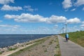 Dutch dike along IJsselmeer with senior cyclists and wind turbines Royalty Free Stock Photo