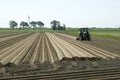 Dutch farmer makes potato ridges in cropland Royalty Free Stock Photo