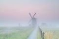 Dutch farmland with windmill in fog Royalty Free Stock Photo